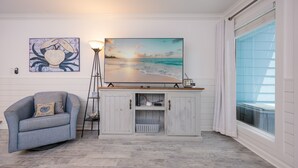 A living room with a sofa, a TV on a wooden cabinet, a painting, and a lamp. - Cinco Brisas 2 3 Bedroom Home (Orange Beach)