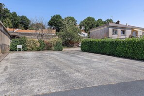 Ein Parkplatz mit Kiesbelag, umgeben von Grünflächen und Wohnhäusern.