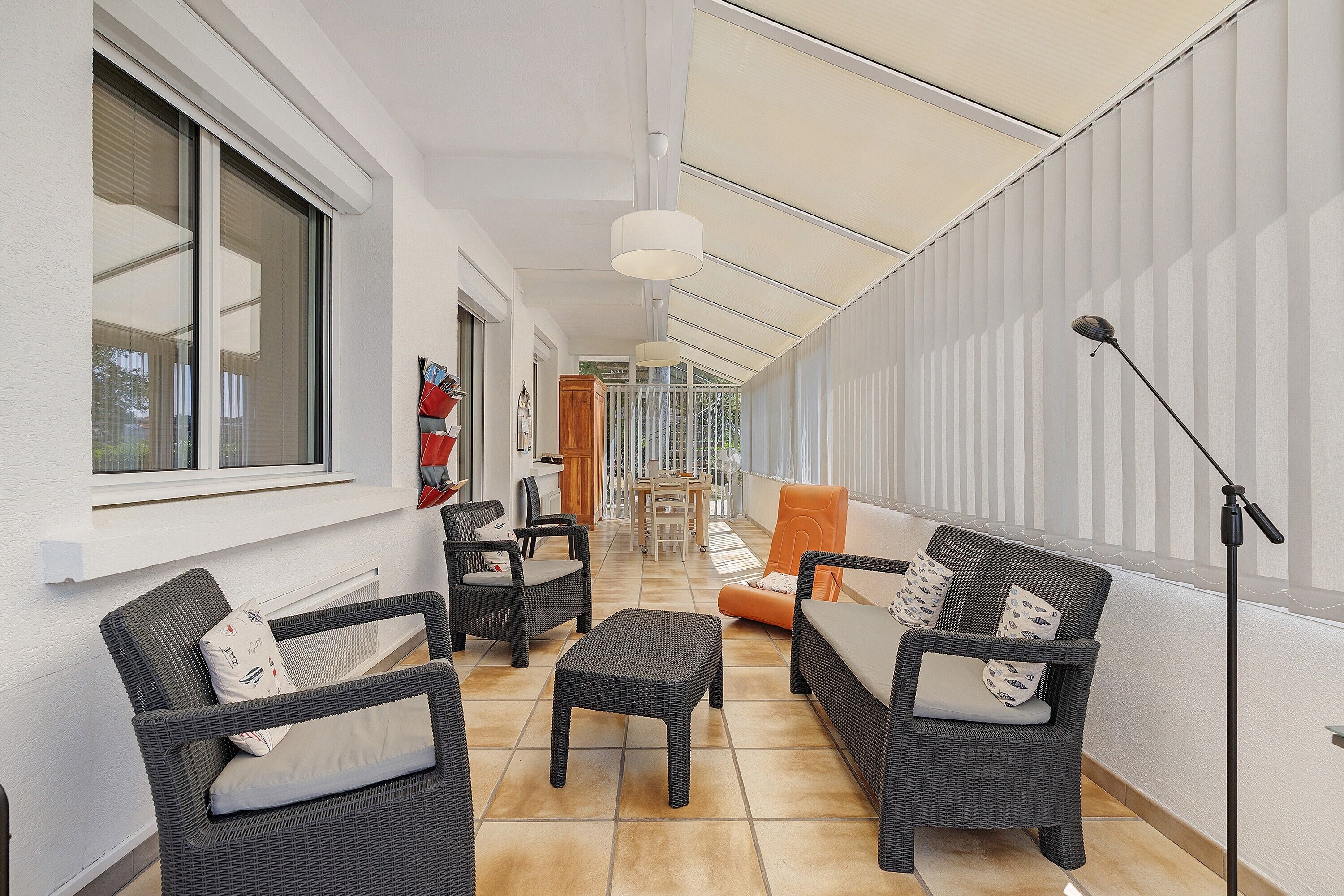 A corridor with wicker furniture, a dining area, and a ceiling fan.