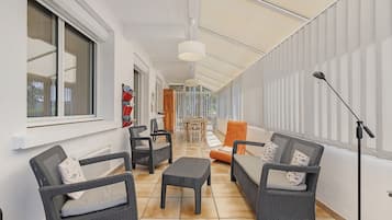 A corridor with wicker furniture, a dining area, and a ceiling fan.