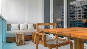 Een moderne woonkamer met een houten eettafel, een bank met kussens en een klein houten krukje.