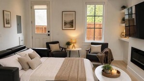 Een moderne slaapkamer met een groot bed, een televisie, een open haard en uitzicht op de omgeving.