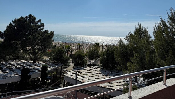 A terrace with outdoor seating, overlooking a beach and the sea. - Hotel Malenri (Golem)