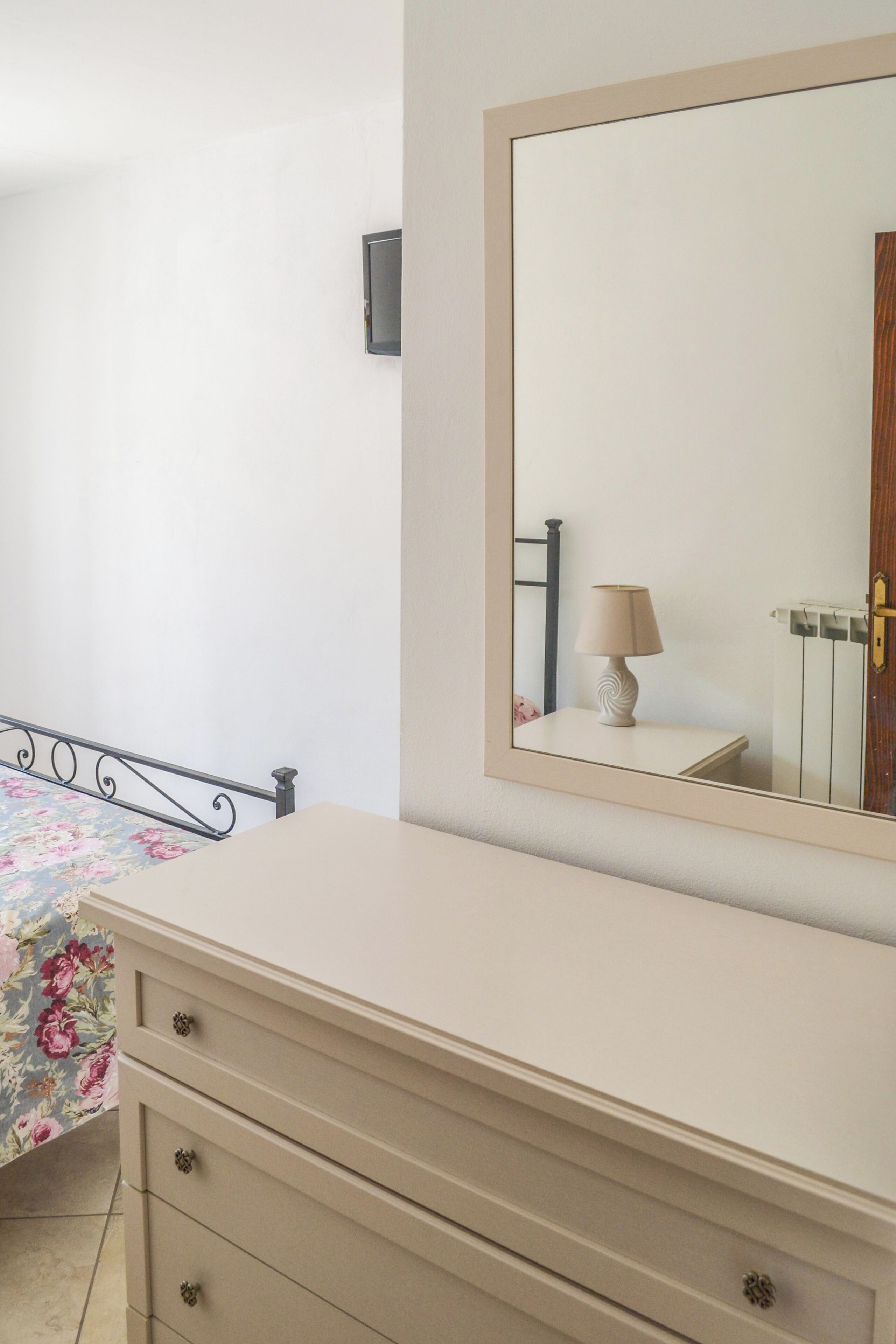 Un dormitorio con cama, cómoda, espejo y puerta.