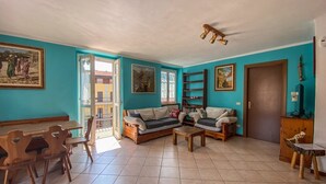 Een woonkamer met een bank, salontafel, houten eettafel, stoelen en een televisie.