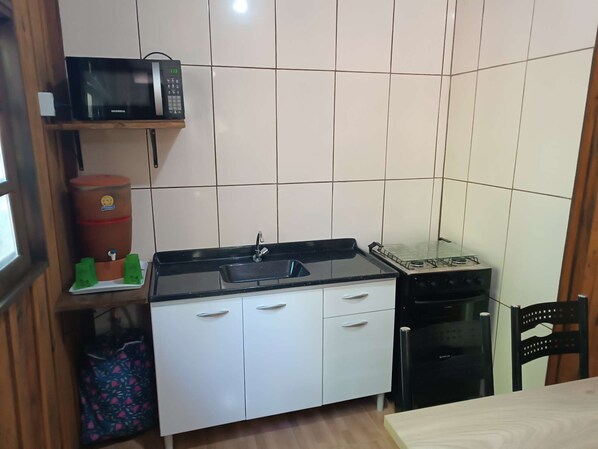 A compact kitchen with a microwave, sink, stove, and cabinets.