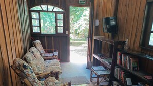 Un interior de madera con un sofá, sillas, una estantería y un televisor.