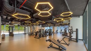 A gym with hexagonal ceiling lights, various exercise equipment, and large windows. - Stylish Top-Floor 1BR with City Views, Close to Dubai Water Canal (Dubai)