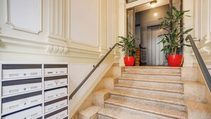 A marble staircase with two red planters on the landing. - Merlot Apartment, Marquês de Pombal, Lisbon (Lisboa)
