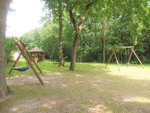 Ein Park mit Schaukeln, einem Picknicktisch und einem Gazebo.
