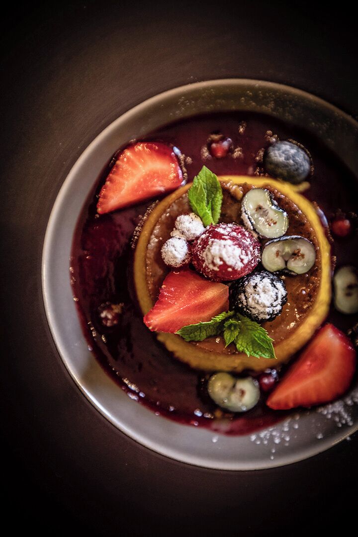 Un dessert composé de fraises, de myrtilles et de feuilles de menthe, présenté dans une assiette.