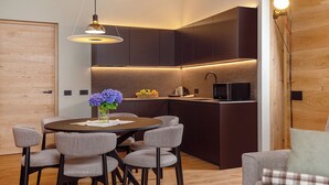 A modern kitchen with dark cabinetry, a built-in microwave, and a dining area with a round table and chairs.
