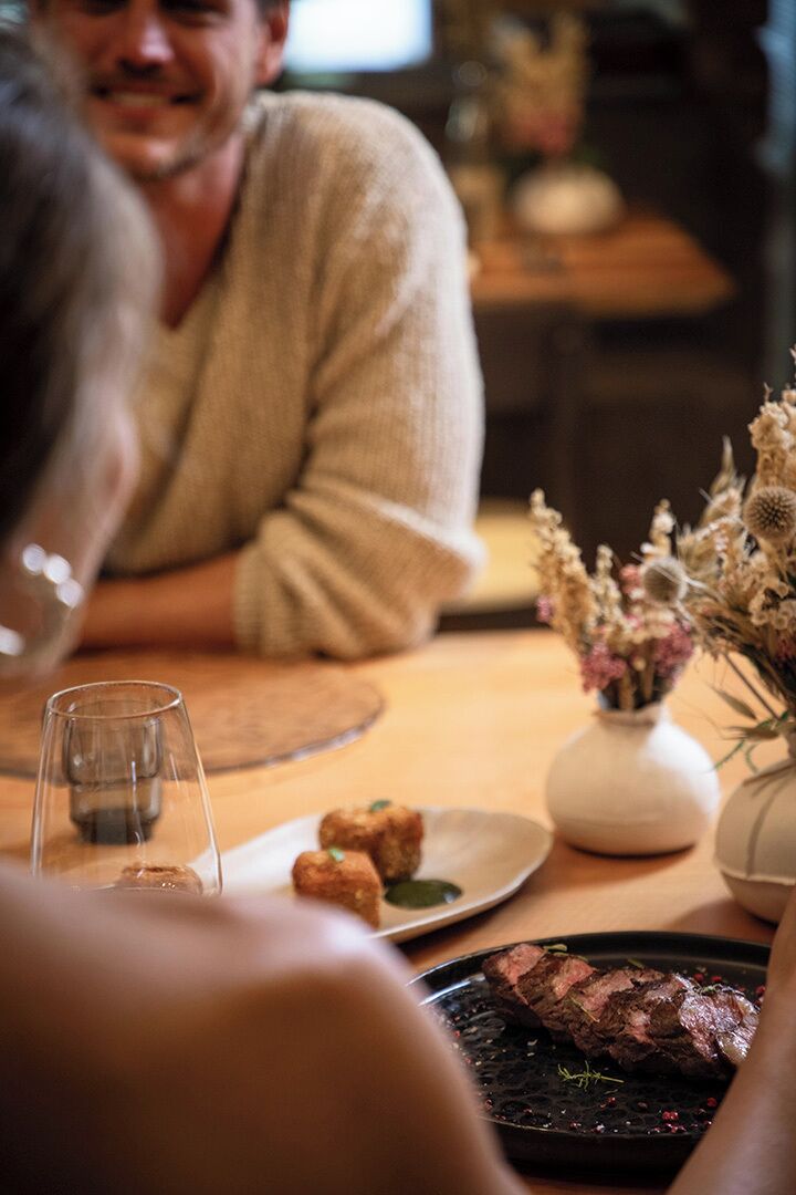 A dining table with a plate of food, a glass of water, and a vase with dried flowers.