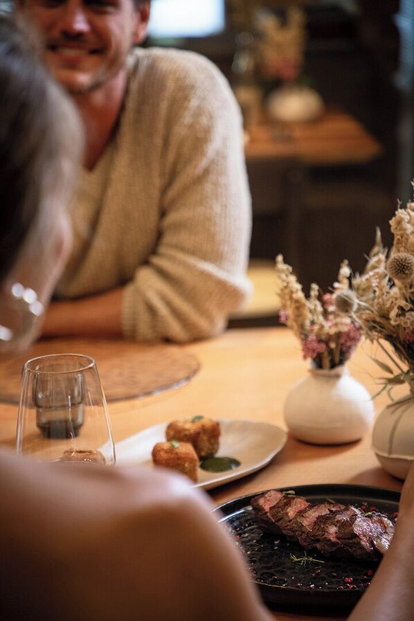 A dining table with a plate of food, a glass of water, and a vase with dried flowers. - LVG Hotel Collection - Cascata d'Otro Mountain Lodge (Alagna Valsesia)