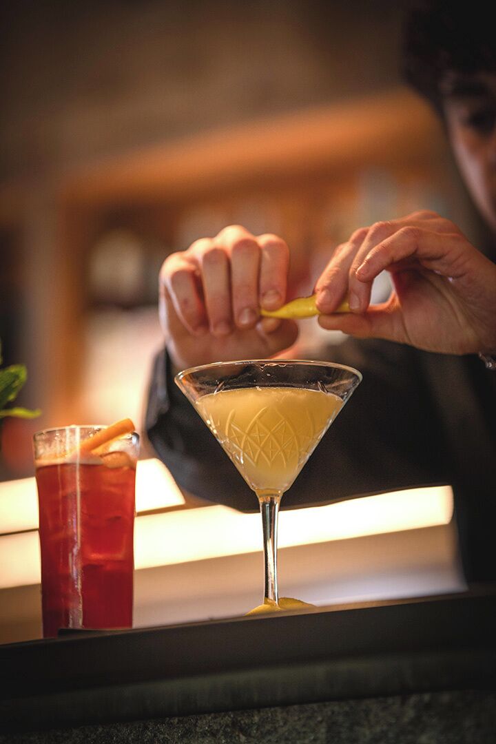 A person pouring a drink into a martini glass.