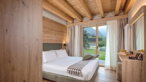 A bedroom with a bed, a wooden headboard, a bedside table, and a view of the outdoors.