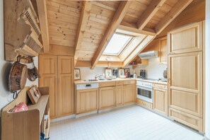 Eine Küche mit Holzschränken, einem Geschirrspüler, einem Backofen und einem Oberlicht.