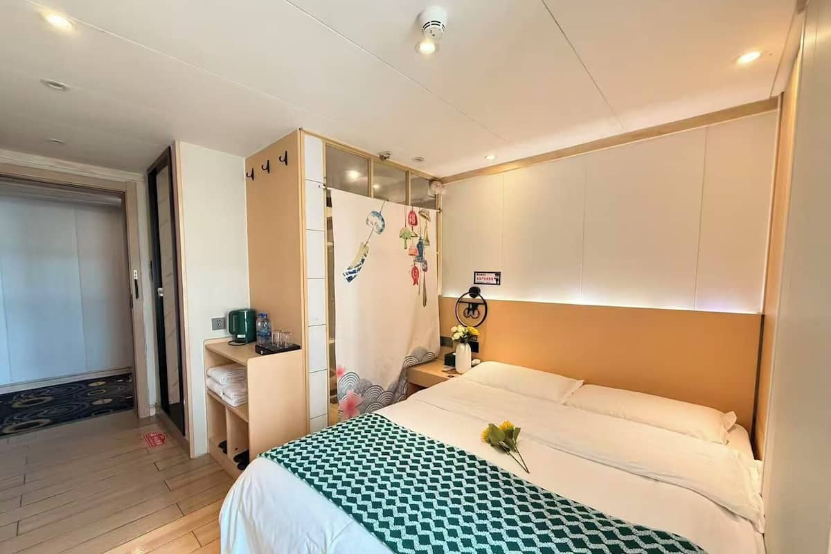 A hotel room with a bed, bedside table, and a wardrobe.
