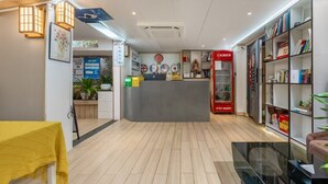 A reception area with a counter, a red vending machine, and a bookshelf with books. - yipingjuminsu (Shenzhen)