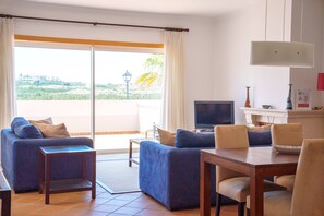 A living room with a sofa, TV, and dining area. - Seaside Light, Praia del Rey (Óbidos)
