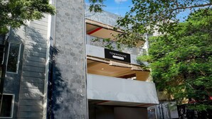 Et moderne rækkehus med balkon, et skilt der angiver, at det er en virksomheds servicerede ejendom, og udsigt til det omkringliggende grønne område.