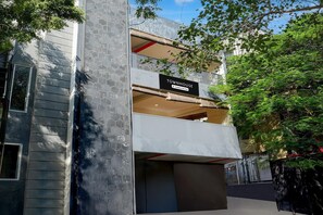 Ein modernes Reihenhaus mit Balkon, einem Schild, das angibt, dass es sich um eine betriebliche Unterkunft handelt, und Blick auf die umliegende Grünfläche.