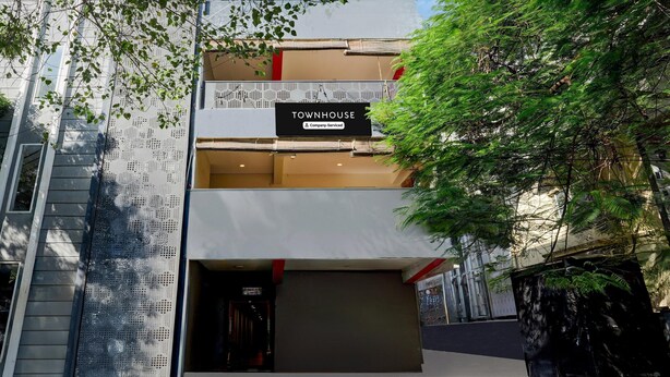 En moderne bygning med et skilt, der viser 'TOWNHOUSE & Company Serviced'.