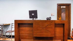 A reception desk with a wooden finish, a computer monitor, and a telephone.