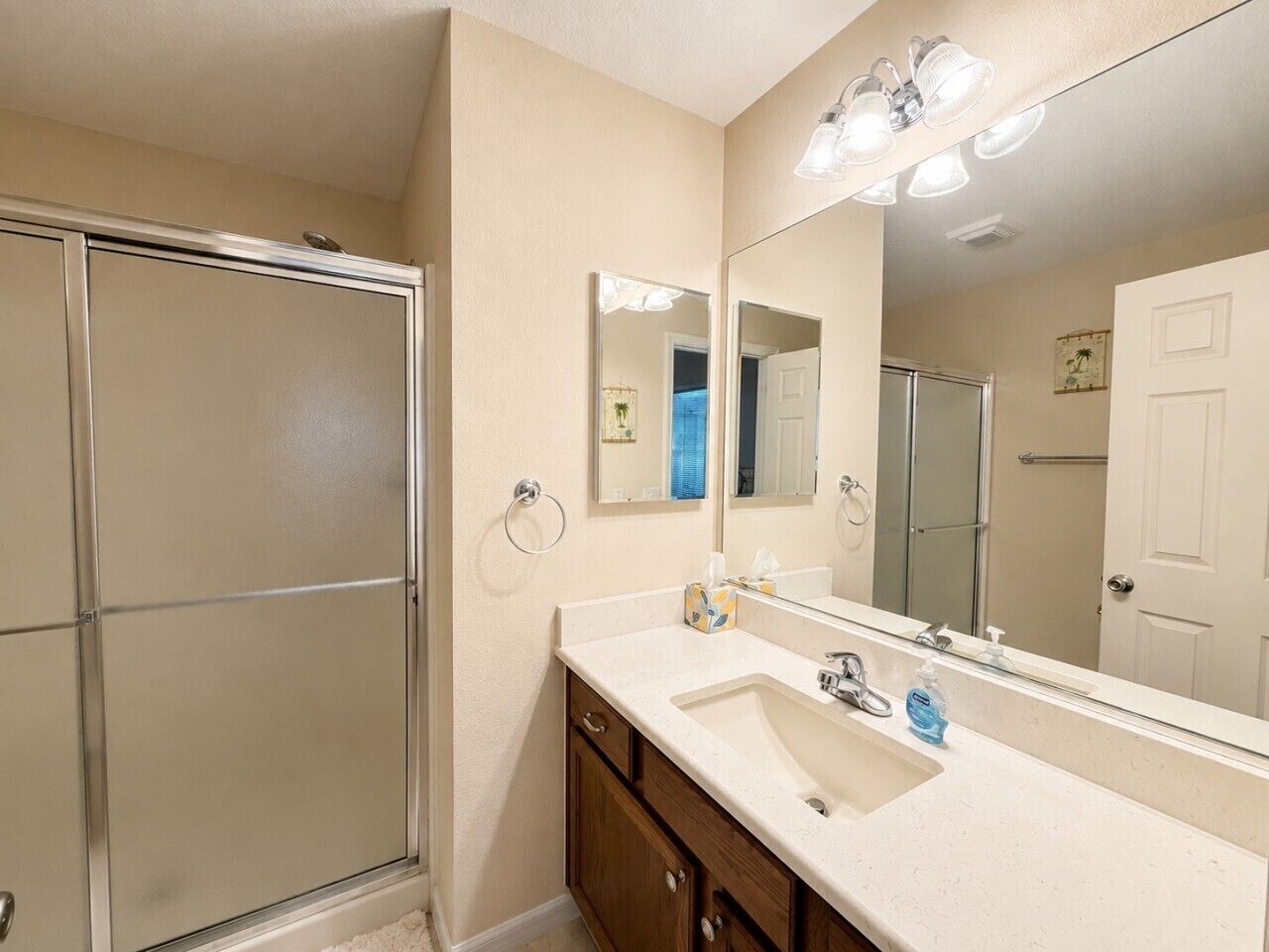 A bathroom with a shower, a sink, a mirror, and a towel rack.