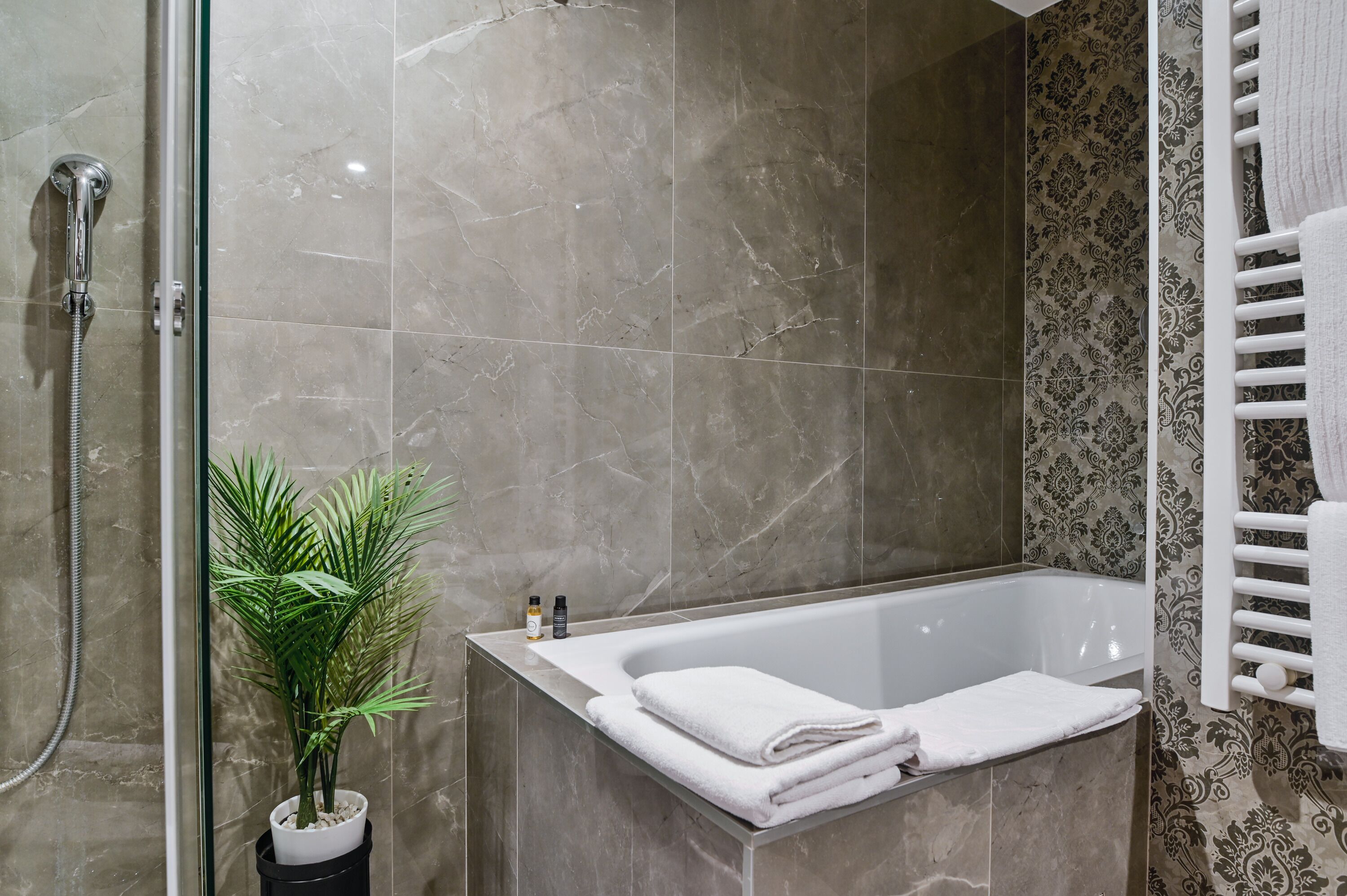Une salle de bain avec une douche, une baignoire, une plante en pot et un porte-serviettes.