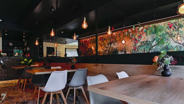 Un comedor moderno con una mesa de madera, sillas grises y lámparas colgantes.
