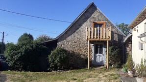 Ein Steinhaus mit einem hölzernen Balkon, einer Tür und einer kleinen Veranda.