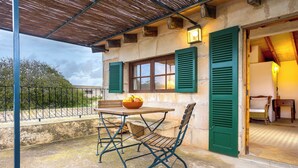 Un patio al aire libre con una mesa, sillas, un tazón de fruta y vistas del entorno.