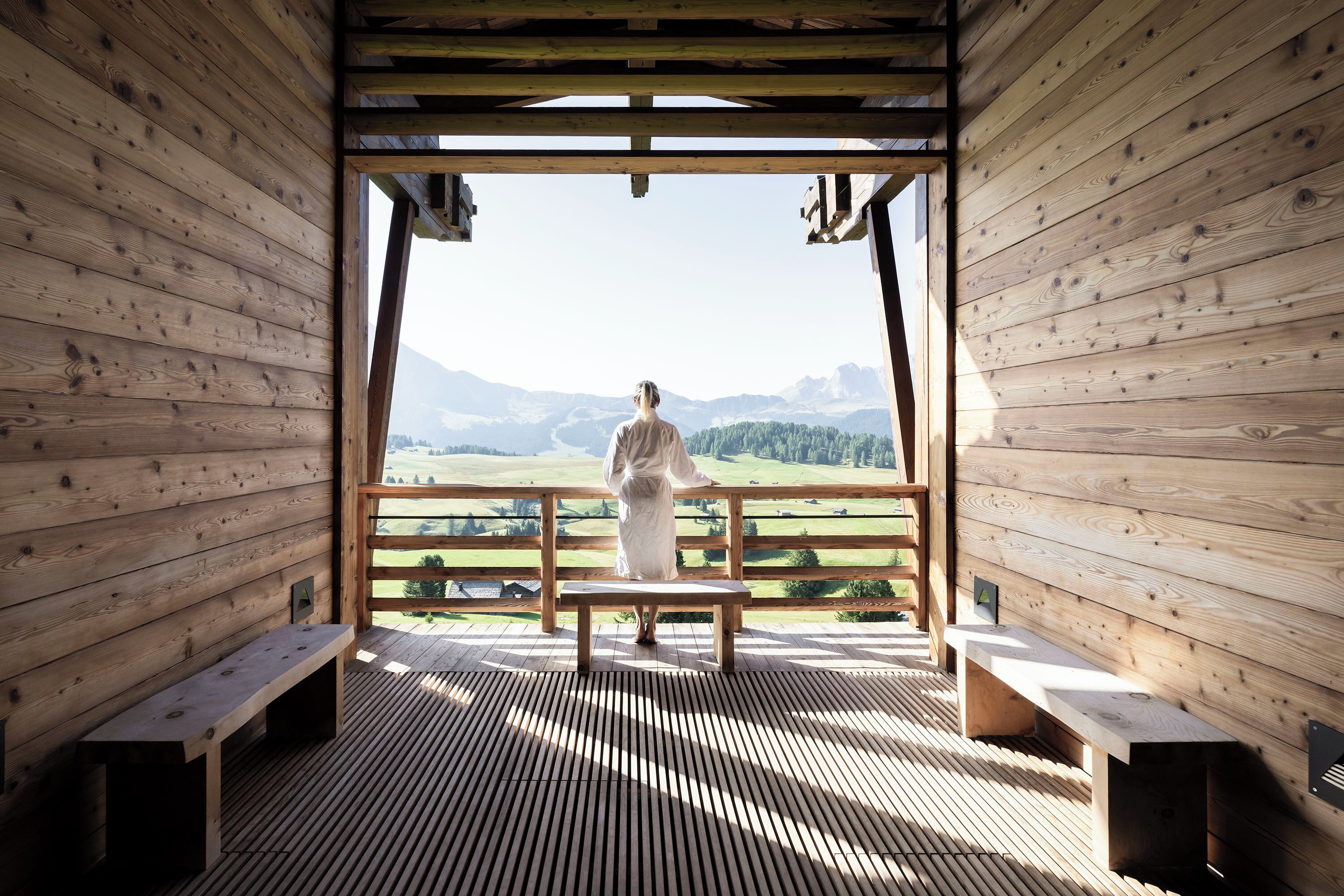 Eine Holzhütte mit einer Bank und Bergblick.