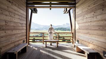 Eine Holzhütte mit einer Bank und Bergblick.