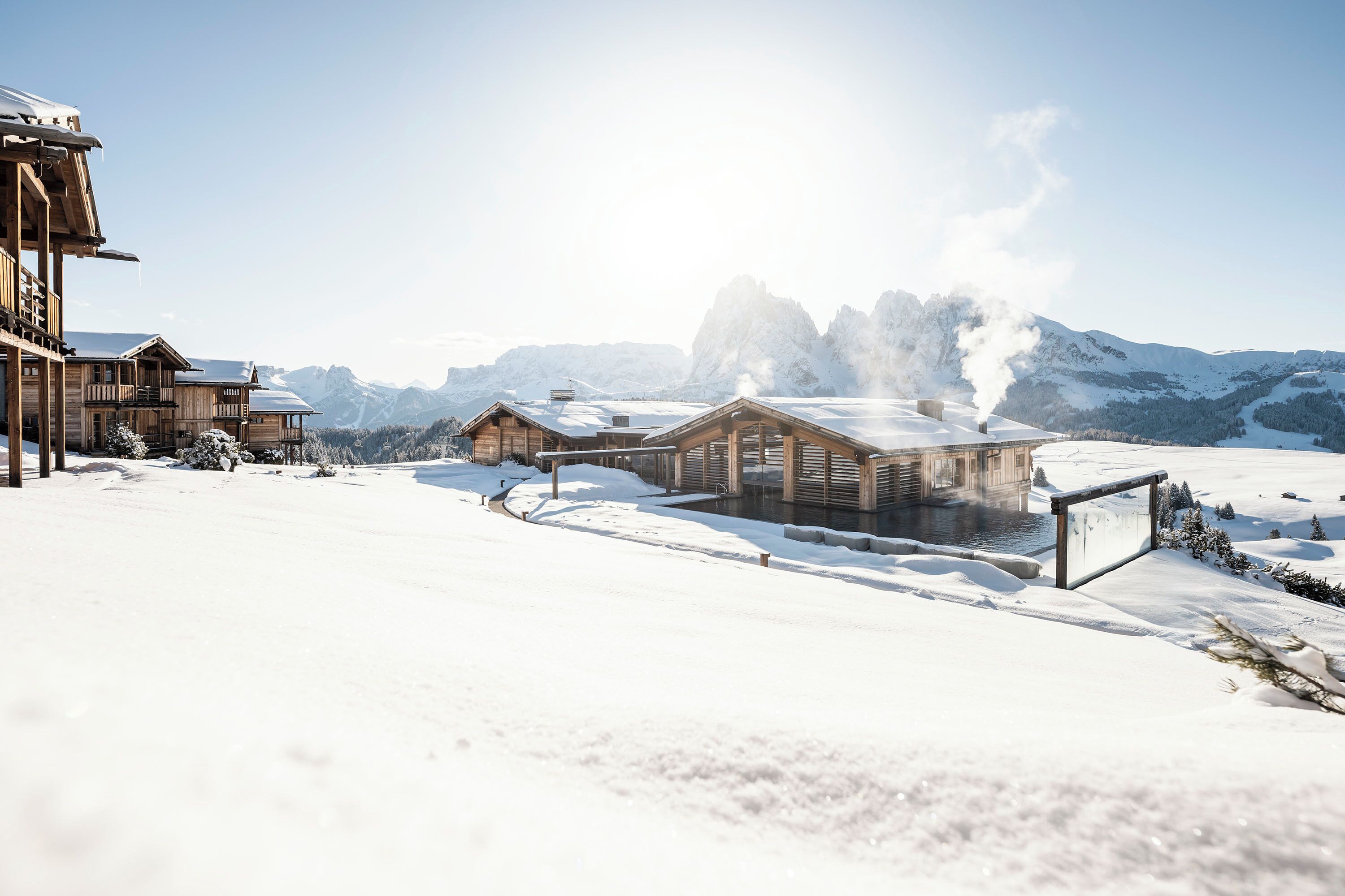 Schneebedeckte Landschaft mit Holzhäusern und blauem Himmel.