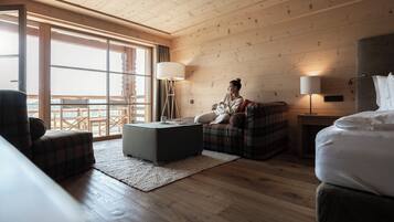 Una habitación acogedora con cama, sofá, sillón, una mesita y una lámpara de pie.