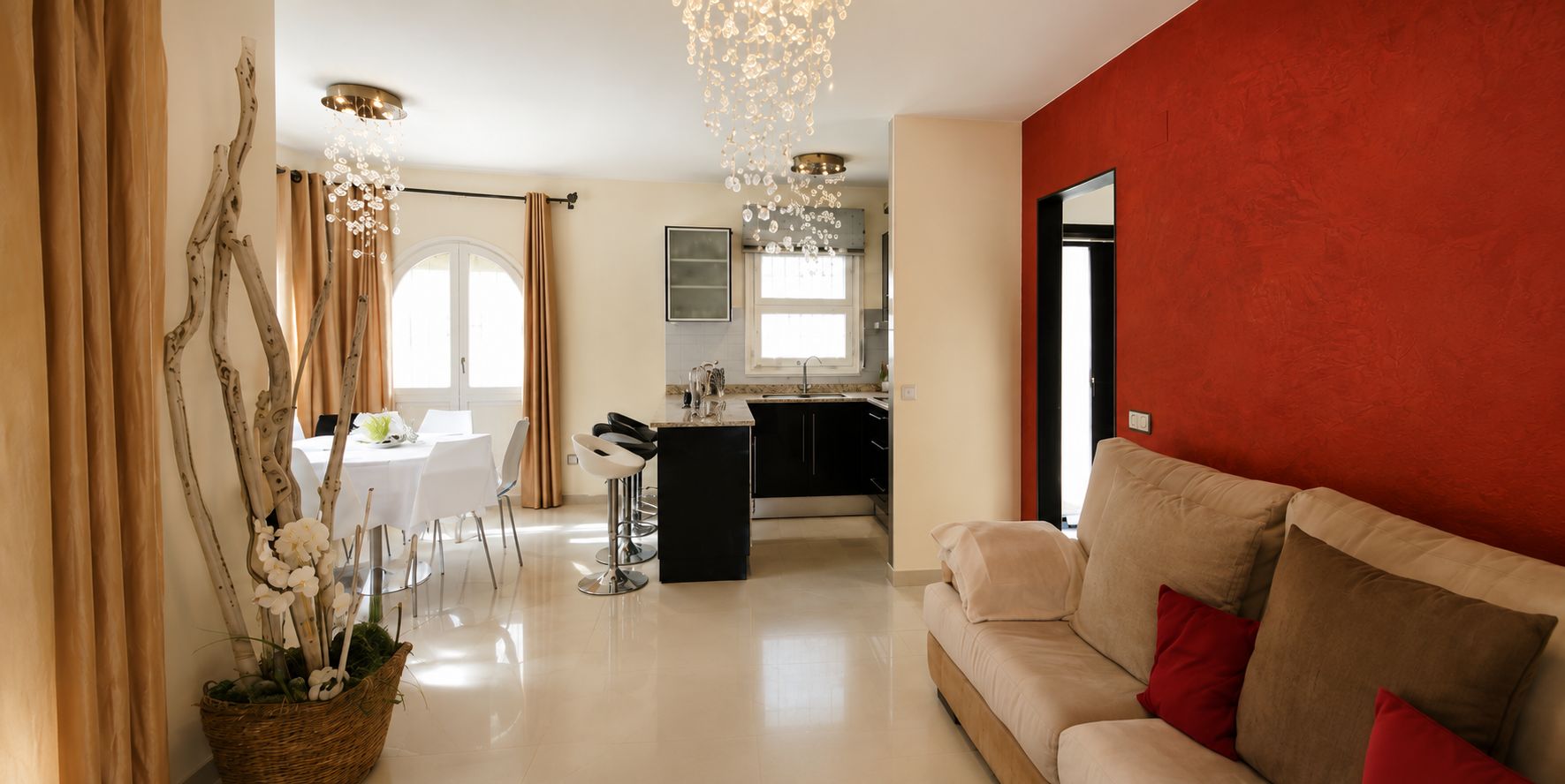 A modern living room with a sofa, a dining area with a table and chairs, and a kitchen in the background.
