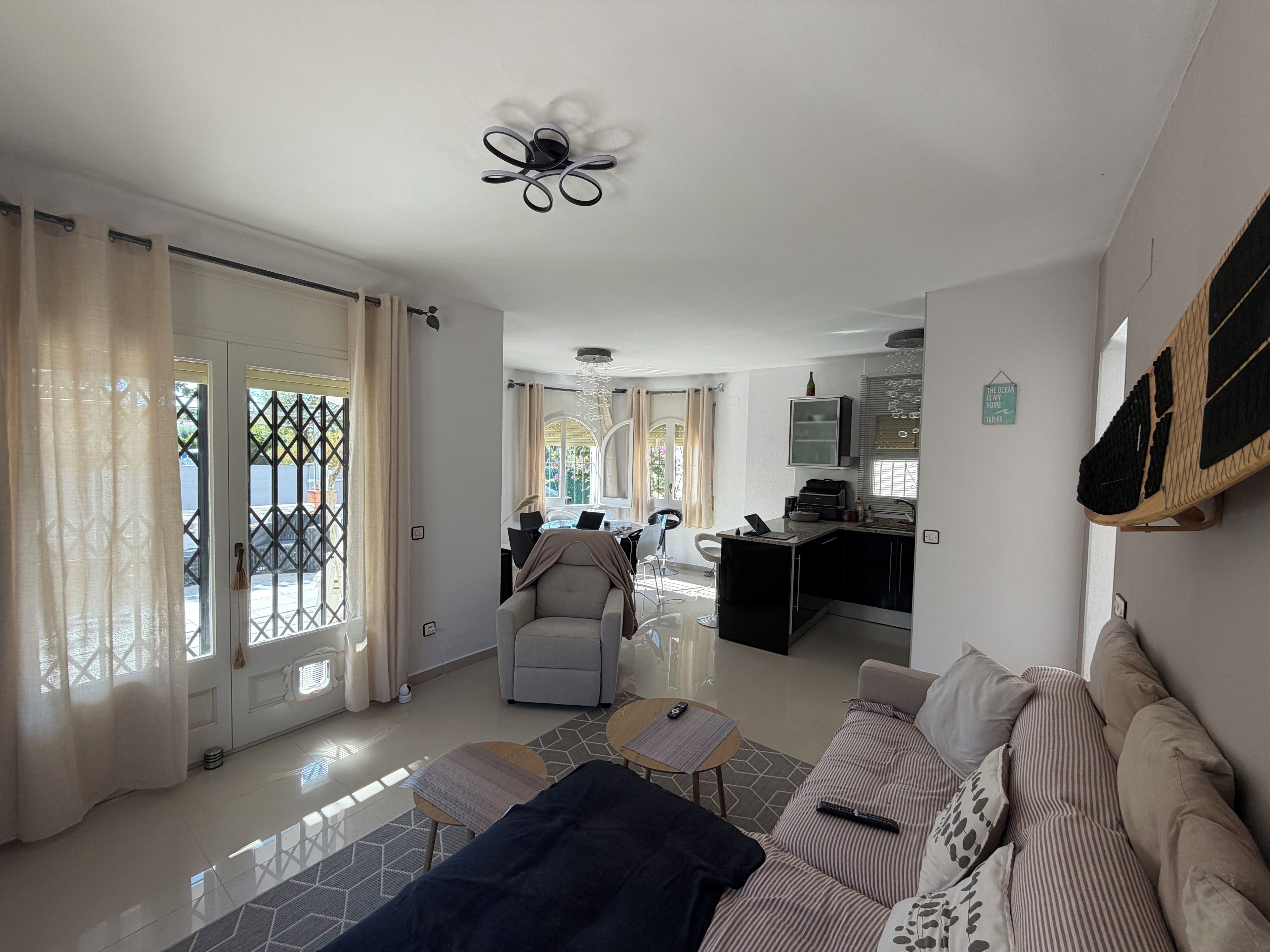 A modern living room with a sofa, a coffee table, and a dining area with a table and chairs.