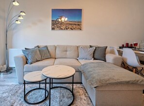Ein Wohnzimmer mit einer Couch, zwei runden Tischen, einer Lampe und einem gerahmten Bild an der Wand.