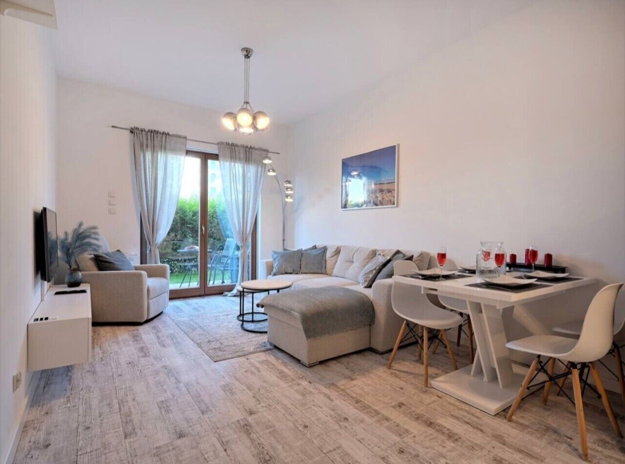 A modern living room with a sofa, dining table, chairs, and a TV.