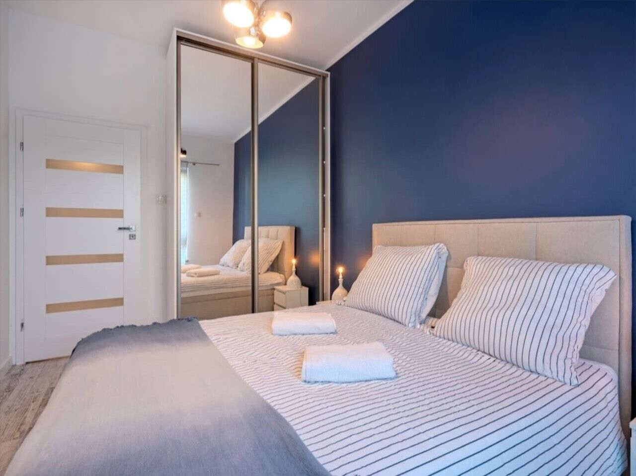 Ein Schlafzimmer mit einem großen Bett, einem Spiegel, Nachttischen und einem Kleiderschrank.