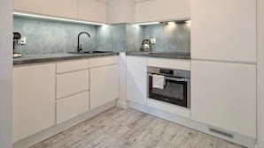 Eine moderne Küche mit weißen Schränken, einem eingebauten Backofen und einer Spüle aus Edelstahl.
