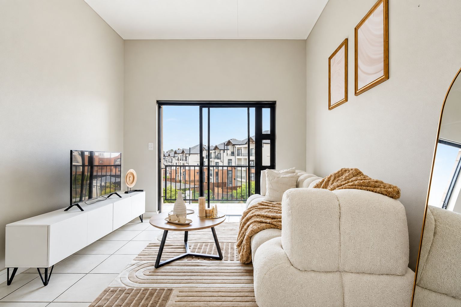 A modern living room with a sofa, a coffee table, and a TV on a white cabinet.