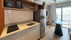 Una cocina moderna con microondas integrado, refrigerador de acero inoxidable, pileta y comedor con mesa y sillas.