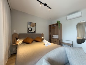 A modern bedroom with a bed, bedside lamps, a hanging plant, a wardrobe, and a mirror. - GA 127Ape com AR prox. Allianz  (São Paulo)
