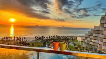 Une vue sur le coucher de soleil depuis un balcon donnant sur une piscine et une zone de loisirs.