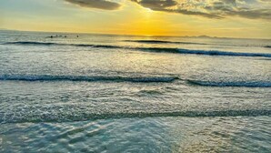 Ein Strand mit Wellen und einem Sonnenuntergang.