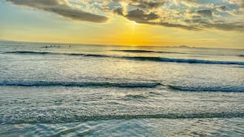 Une plage avec des vagues et un coucher de soleil.