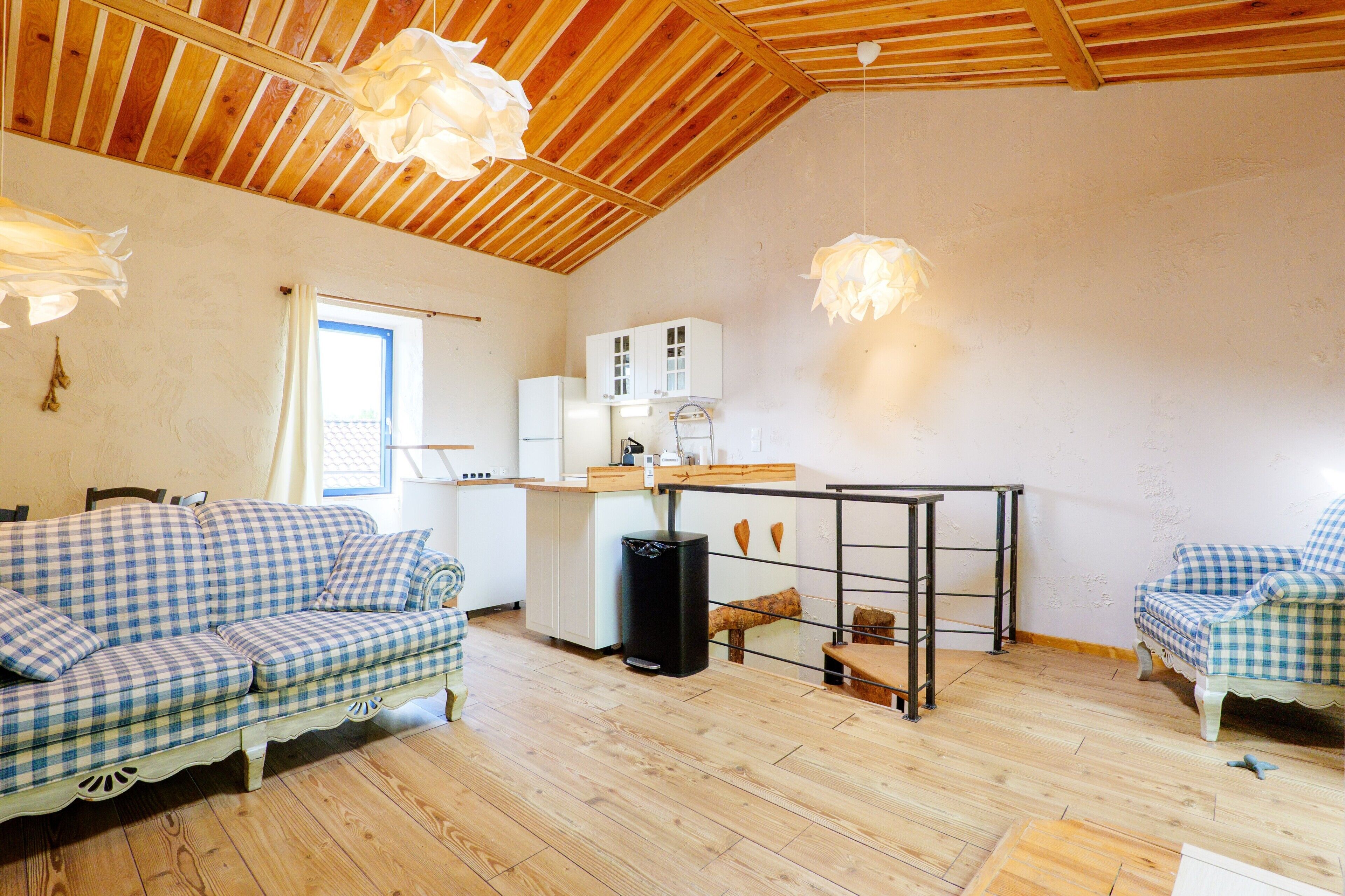 A cozy room with a wooden ceiling, a kitchenette, a sofa, and a dining table.